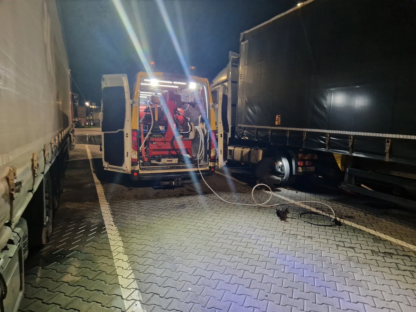 Naprawa opony TIR-a w nocy przy świetle lamp serwisowych